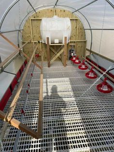 the inside of a greenhouse with metal grates and red buckets on the floor