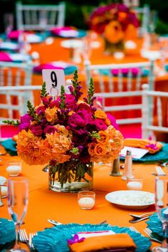 the table is set with orange and pink flowers