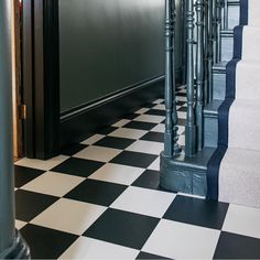 a black and white checkered floor with metal handrails next to the stairs