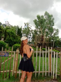 a woman standing in front of a wooden fence