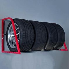 there is a red car tire rack with four tires on it's sides and two wheels attached to the wall