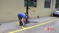 a man bending over to fix a bike on the ground in front of a building