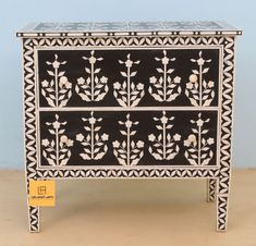 an ornate black and white cabinet with flowers on it