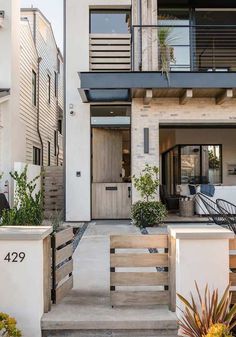 the front entrance to a house with stairs leading up to it and plants in pots on either side