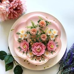 a plate with pink flowers on it next to purple flowers