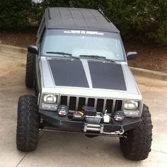 the jeep is parked on the side of the road in front of some bushes and trees