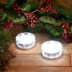 two clear plastic plates sitting on top of a wooden table next to christmas greenery