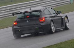 a grey car driving down a race track with its rear lights on and the back end of it's bumper