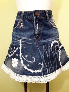 a denim skirt with white lace on the bottom and flowers painted on it, sitting on a mannequin