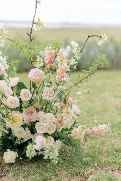 a bouquet of flowers sitting on the ground in front of a tree with white and pink flowers