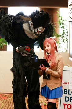 two people in costumes standing next to each other and looking at a piece of paper