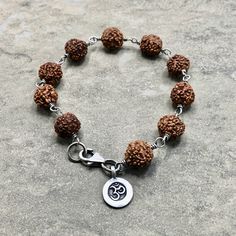 "Lovely Rudraksha Seed Beads wrapped in oxidized sterling silver with a Hilltribe fine silver OM charm. This beaut is 7 1/4\" and closes securely with a sterling silver lobster clasp. Rudraksha is worn at all times or kept close to the skin, it is a sacred seed that emits a potent protective energy, enabling the wearer to achieve their greater potential." Spiritual Sterling Silver Beaded Bracelets, Artisan Hand-strung Sterling Silver Beaded Bracelets, Handmade Adjustable Sterling Silver Rosary Bracelet, Silver Spiritual Bracelet With 8mm Beads, Spiritual Beaded Bracelets With Sterling Silver Clasp, Symbolic Silver Bracelets With 8mm Beads, Nickel-free Brown Spiritual Beaded Bracelets, Holistic Silver Bracelet With Round Beads, Holistic Silver Bracelets With Round Beads