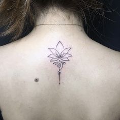 the back of a woman's neck with a flower tattoo on it