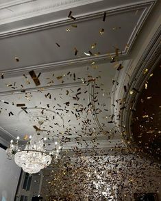 a room filled with lots of gold confetti and chandelier hanging from the ceiling