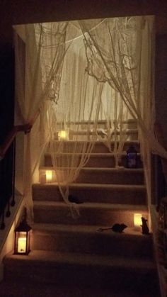 candles are lit on the steps leading up to an open window with sheer curtains over it