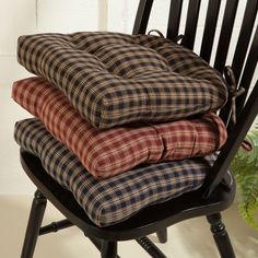 three cushions stacked on top of each other in a black rocking chair next to a potted plant