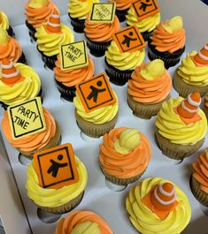 cupcakes with yellow frosting and orange icing are arranged in a box