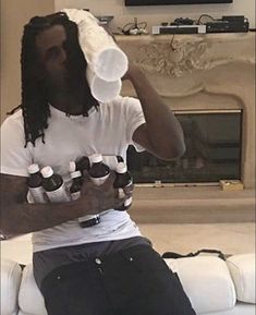 a man sitting on top of a white couch holding six bottles of beer in his hands