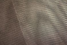 a close up view of the texture of a metal mesh fabric, which is brown and white