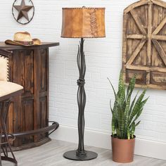 a floor lamp next to a potted plant in a room with white brick walls