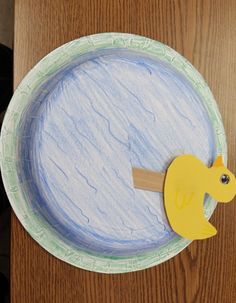 a paper plate with a yellow duck on it's side and a piece of wood sticking out of the middle