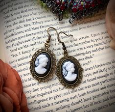 Inspired by the elegant style of early Nineteenth-century England, these beautifully hand-made dangle earrings are lightweight and the perfect accessory for any outfit! The pretty but simple cameo setting allows them to be worn with casual or formal attire.  Earring characteristics: -Metal Antique Brass French hook -Rubber earring back for extra security  -Black Resin Cameo Charms -Drop length: 1.25 inches  See the beautiful matching necklace here, which can be personalized: https://etsy.me/3bLh Blue Beaded Bracelets, Cameo Earrings, Gorgeous Bracelet, Formal Attire, Matching Necklaces, Blue Earrings, The Pretty, Earring Backs, Light Purple