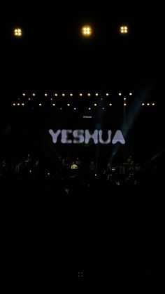 the yesmua logo is lit up at night in front of a stage full of people