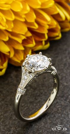 a diamond ring sitting on top of a table next to a yellow and white flower