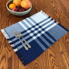 a bowl of fruit sitting on top of a wooden table next to a blue and white checkered napkin