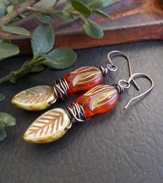 "Colorful woodland earrings featuring beautiful Czech glass beads. The flower drops are a bright koi orange with a rustic gold metallic finish. The leaves are light green with a terracotta and caramel finish. I've wrapped the beads with solid copper wire which I have oxidized. I made matching solid copper ear wires. These earrings are a fun addition to your boho collection and a great gift for someone who loves nature or rustic style. You can select copper niobium or copper plated lever back ear Unique Orange Flower-shaped Jewelry, Unique Orange Flower Shaped Jewelry, Orange Czech Glass Jewelry With Ear Wire, Orange Adjustable Dangle Flower Earrings, Orange Bohemian Flower Earrings For Gift, Bohemian Orange Flower Earrings For Gift, Artistic Orange Jewelry With Matching Earrings, Artistic Orange Drop Earrings, Bohemian Orange Flower Jewelry