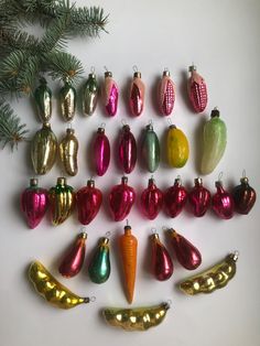 an assortment of christmas ornaments are arranged on a white surface next to a fir tree