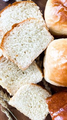 several loaves of bread sitting on top of a wooden table next to some dipping sauce