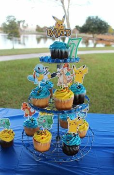 cupcakes are arranged on a cake stand in front of a lake and park