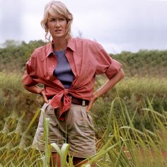 a woman standing in tall grass with her hands on her hips