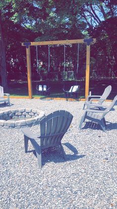 several lawn chairs sitting on gravel in front of a swing set