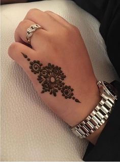 a woman's hand with a henna tattoo on her left arm and wrist