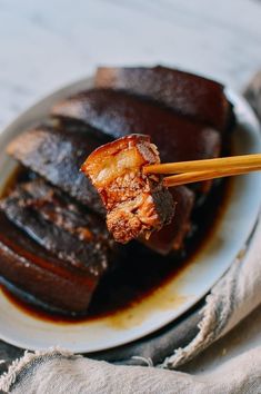 chopsticks holding up some meat on a plate