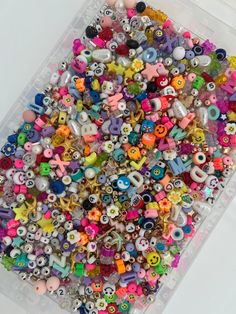 a plastic container filled with lots of different types of beads and charms on top of a table