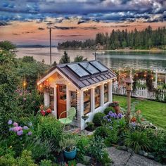 a small house sitting on top of a lush green field next to a body of water