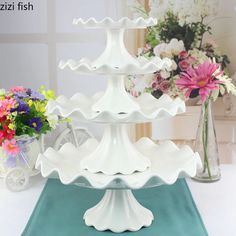 three tiered cake stand with flowers in the background