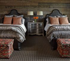 two beds in a room with wooden walls and carpeted flooring next to each other