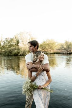 a man and woman standing next to each other near the water