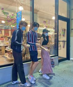 three people wearing face masks standing in front of a store