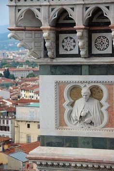 a statue on the side of a building with a city in the backgroud