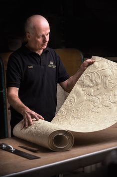 a man is working on an intricately carved piece of paper