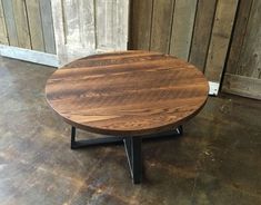 a round wooden table sitting on top of a hard wood floor next to a wall