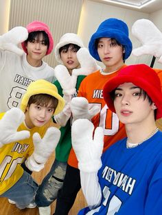 four boys wearing hats and gloves posing for a photo in front of a mirror with their hands up to the camera