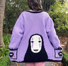 a woman wearing a purple sweater with a face drawn on it