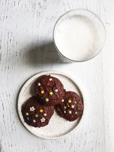 chocolate cookies with sprinkles on a plate next to a glass of milk