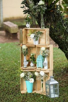 a wooden crate with flowers and vases on it sitting in the grass next to a tree